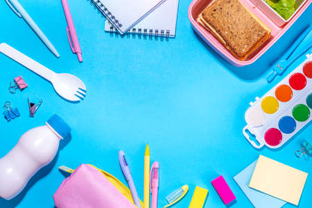 Healthy school meal, back to school concept. Children packed lunch box with balanced diet snack food - yogurt, cereal toast sandwich, apple, fresh vegetable salad, high-colored bright backgroundの写真素材