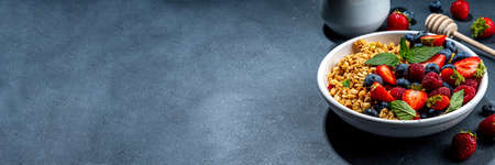 Healthy breakfast granola with fresh berry - strawberry, raspberry, blueberry on black backgroundの写真素材