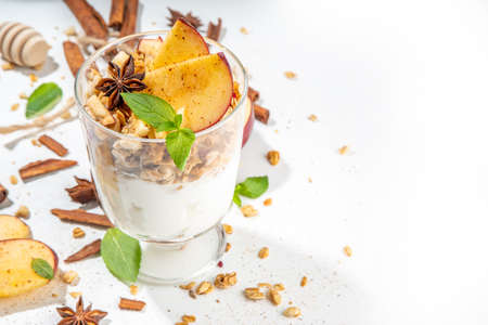 Apple Pie Granola Cheesecake, breakfast snack layered dessert with oat granola, cream cheese yogurt, honey, apple slices and cinnamon spices on white background copy spaceの写真素材
