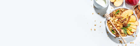 Healthy autumn breakfast granola. Apple pie granola with muesli, cinnamon spices, apples slices, honey and nuts, on white stone background copy spaceの写真素材