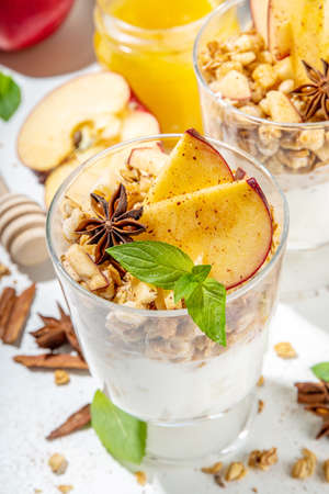 Apple Pie Granola Cheesecake, breakfast snack layered dessert with oat granola, cream cheese yogurt, honey, apple slices and cinnamon spices on white background copy spaceの写真素材