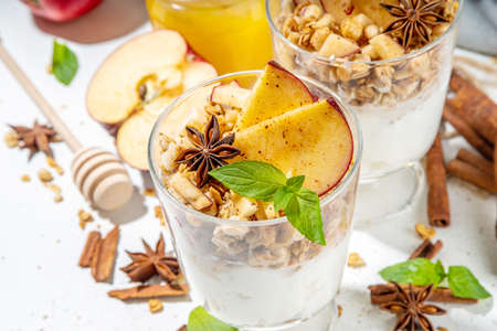 Apple Pie Granola Cheesecake, breakfast snack layered dessert with oat granola, cream cheese yogurt, honey, apple slices and cinnamon spices on white background copy spaceの写真素材
