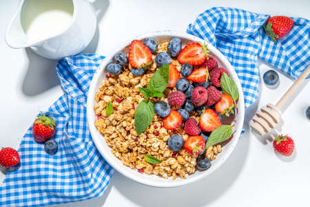 Healthy breakfast granola with fresh berry - strawberry, raspberry, blueberry on white backgroundの写真素材