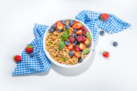 Healthy breakfast granola with fresh berry - strawberry, raspberry, blueberry on white backgroundの写真素材