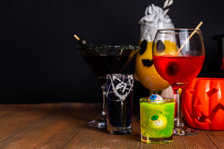 Halloween party bar festive drink, set various colorful alcohol, non-alcohol cocktails, drinks with halloween characters costumes hands, holiday decor and symbolsの写真素材