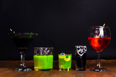 Halloween party bar festive drink, set various colorful alcohol, non-alcohol cocktails, drinks with halloween characters costumes hands, holiday decor and symbolsの写真素材