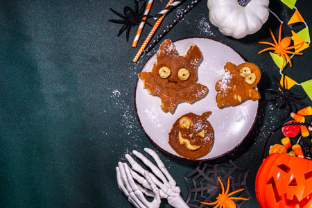 Halloween creative kids breakfast. Cute homemade pancakes in the shape of Halloween holiday symbols - bat, jack pumpkin, ghost, made by cookie cuttingsの写真素材