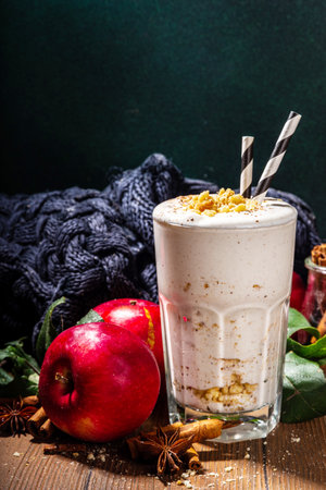 Homemade loaded apple pie milk shake, red autumn apple protein smoothie with tart crumble and spices, healthy fall seasonal breakfast drink, on cozy wooden background copy spaceの写真素材