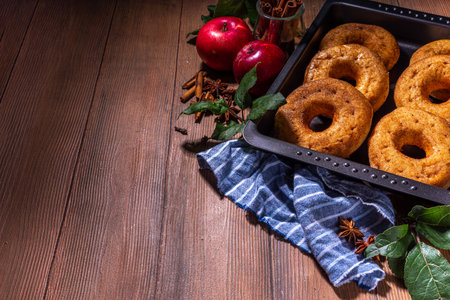 Traditional tasty ready to eat apple cider donuts. Homemade baked apple cinnamon donuts with apple pie crumble and spices, served on wooden table copy spaceの写真素材