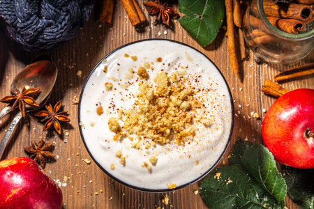Bowl of homemade apple pie yogurt ready for breakfast, with tart crumble topping. On wooden background with red autumn apples and spices, copy spaceの写真素材