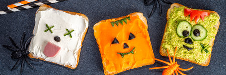 Kids food, party or breakfast Halloween idea. Simple healthy sandwiches recipe from toast bread, avocado, cream cheese, pumpkin spread with Halloween monster decorの写真素材