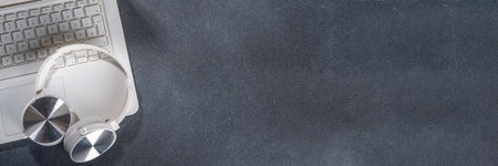 Headphones and laptop on classic black table. Elegant simple office working background, minimal workplace flat lay copy spaceの写真素材