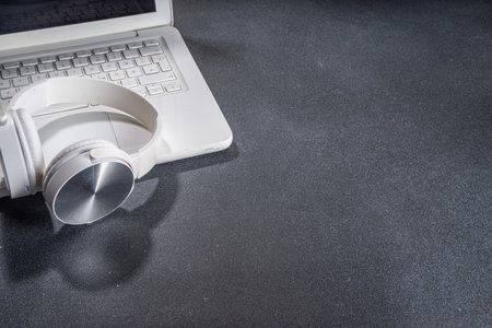 Headphones and laptop on classic black table. Elegant simple office working background, minimal workplace flat lay copy spaceの写真素材