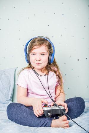 Kids Gaming video games concept. Toddler or young girl, playing game with joystick, smart-phone, VR...