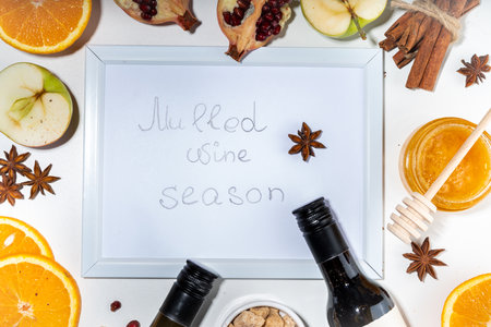 Different mulled wine ingredients set on white background, flat lay with wine bottle, cinnamon, apple, orange, anise star, simple autumn food drink cooking backgroundの写真素材