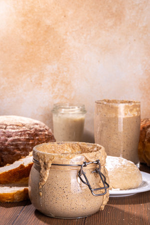 Healthy lifestyle, gluten free fermenting diet. Homemade sourdough. Active bubbly rye, wheat, oat sourdough with different flour and fermentation methods, in glass jars, with raw dough and baked breadの写真素材