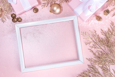 Rose gold Christmas, New Year background with golden christmas tree twigs and balls, holiday gift boxes, decorations, artifical snow, flat lay on pink background copy spaceの写真素材