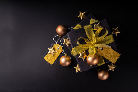 Merry Christmas Happy Holidays greeting card background, New Year,  Noel, Winter xmas holidays flat lay. Christmas golden ornaments, decor fir tree, gift boxes on black background top view copy spaceの写真素材