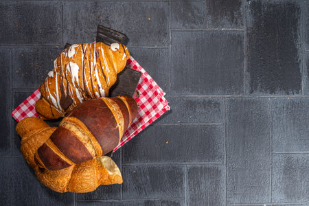 Freshly baked croissants with coffee espresso cup on black tiled background top view copy spaceの写真素材