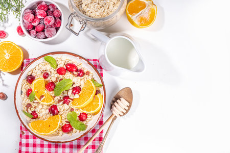 Christmas morning breakfast recipe, cranberry orange oatmeal. Cooked oats porridge with fruit and berry, on white table top view copy spaceの写真素材