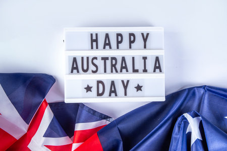 Australia Day greeting card Background with  australian flag, silver stars, lightbox with text Happy Australia day, paper red, blue, white decor, over white background copy spaceの写真素材