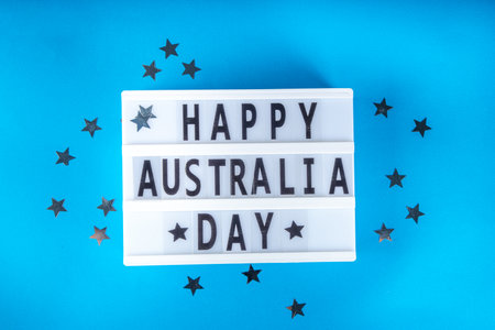 Australia Day greeting card Background with  australian flag, silver stars, lightbox with text Happy Australia day, paper red, blue, white decor, over blue background copy spaceの写真素材