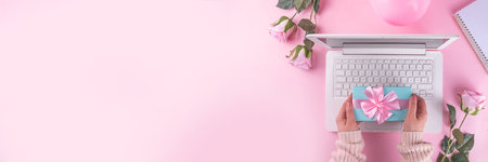 Romantic holiday background. March 8 women's day, valentine's day preparation flatlay, with laptop, pink roses flower bouquet, gift box, notepad, on cute pink background copy spaceの写真素材