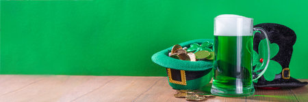 Beer glasses with leprechaun hat, shamrock clover leaves, traditional decorations for St. Patrick's Day, on green wood background. St. Patrick's Day Ireland holiday greeting card, invitation backgroundの写真素材