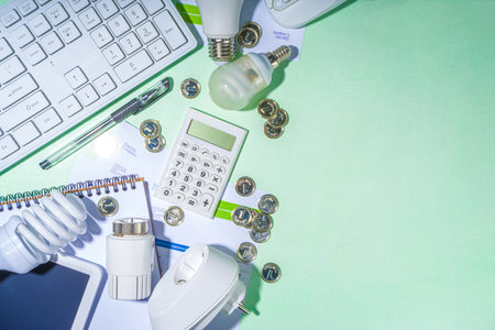 Energy saving with modern modernization technology and devices. Electricity bills, LED bulbs, heat thermostat, calculator on light green table copy space. Go green, energy costs conceptの写真素材