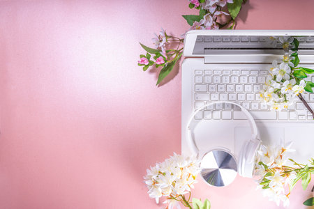 Spring office workplace, blogging flat lay background. White laptop, with headphones, tablet, spring...