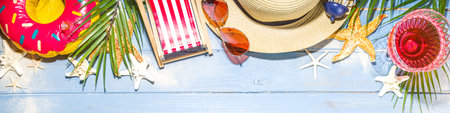 Summer beach holiday  vacation and travel background with deck chair, Lifebuoy, cocktail, tropical leaves, sand, sunglasses, sea shells starfish. Blue sun lighted wooden background copy spaceの写真素材