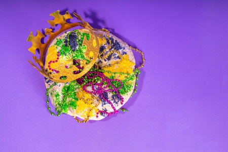 King Cake for Mardi Gras, traditional New Orlean Mardi Gras holiday pastry with plastic baby, with festival masquerade accessories, decor, carnival mask, beadsの写真素材