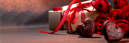 Chocolate hearts with red roses, gift box, on dark brown background copy space. Valentine's Day greeting card backgroundの写真素材