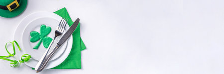 St. Patrick's Day festive table setting. Plate and cutlery with green napkin, shamrock symbol, gold horseshoe decor for luck. Patrick Day menu background, party invitation, top view copy spaceの写真素材