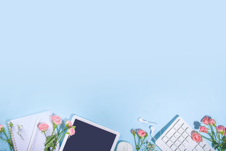 Spring office desk flatlay with keyboard, notepad, tablet, mouse, headphones, spring flowers and...