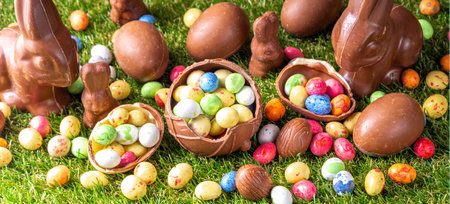 Easter egg hunting background. Various candy and chocolate Easter eggs, bunny and rabbits with...