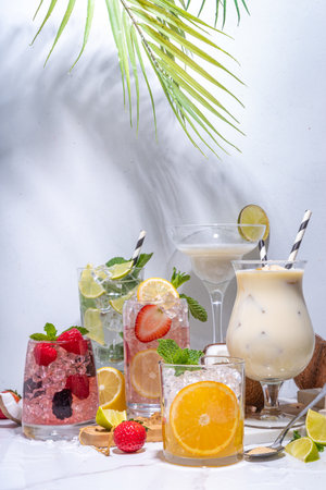 Summer cocktails drinks. Classic alcoholic long drink mocktail versions, various beverages, lemonades with berries, lime, orange, coconut, ice on white marble backgroundの写真素材