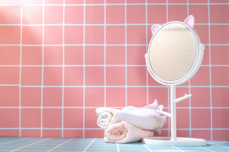 Cute pink empty bath shelf background with stack of towels and mirror, woman girl bathroom background with space for your product or textの写真素材