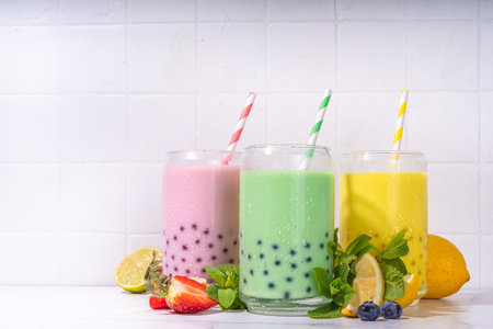 Set of three colorful summer bubble tea, bright creamy pearl tea or latte tapioca drinks, pink berry, yellow citrus, green mint, with tapioca balls and crushed ice, on white backgroundの写真素材