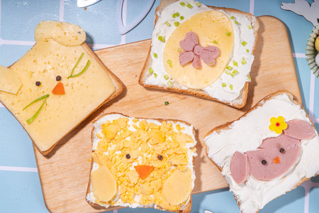 Cute funny Easter breakfast for kids. Homemade sandwiches, sandwiches in the form of symbols of the Easter holiday - Sheep, bunny rabbit, Easter egg, chicken.  top view copy spaceの写真素材