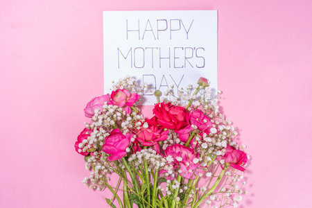 Moms day greeting card, invitation background, Spring bouquet of beautiful ranunculus flower, with cute craft paper gift bow and note Happy Mothers day, copy space on white backgroundの写真素材