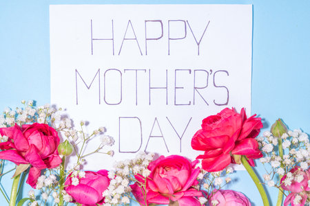 Moms day greeting card, invitation background, Spring bouquet of beautiful ranunculus flower, with cute craft paper gift bow and note Happy Mothers day, copy space on white backgroundの写真素材