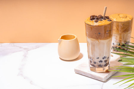 Boba dalgona coffee. Trendy asian latte morning drink with whipped instant coffee and tapioca pearl balls, summer thai bubble cocktail glass in sunny backgroundの写真素材