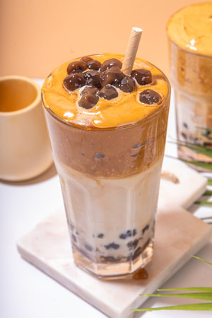 Boba dalgona coffee. Trendy asian latte morning drink with whipped instant coffee and tapioca pearl balls, summer thai bubble cocktail glass in sunny backgroundの写真素材