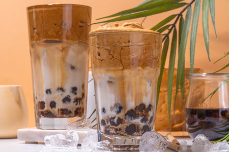 Boba dalgona coffee. Trendy asian latte morning drink with whipped instant coffee and tapioca pearl balls, summer thai bubble cocktail glass in sunny backgroundの写真素材