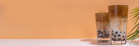 Boba dalgona coffee. Trendy asian latte morning drink with whipped instant coffee and tapioca pearl balls, summer thai bubble cocktail glass in sunny backgroundの写真素材