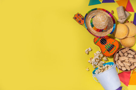 Brazilian Festa Junina Summer Festival, holiday greeting card, invitation Background. Brazilian straw hat, popcorn, peanuts, guitar, corn cookies, with colorful flags on yellow backgroundの写真素材
