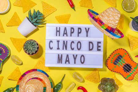 Mexican Cinco de Mayo holiday background with mexican cactus, nachos chips, guitars, sombrero hat and chilli pepper, Bright yellow flat lay with traditional Cinco de Mayo decor and party accessoriesの写真素材