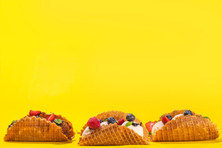 Various sweet taco ice creams. Waffle taco shells with chocolate and vanilla flavour ice cream with different fruits, berry, toppingsの写真素材