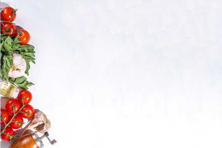 White cooking background with useful cooking italian Mediterranean ingredients - tomatoes, parsley greens, olive oil, salt, pepper, garlic, flat lay white table top view copy spaceの写真素材